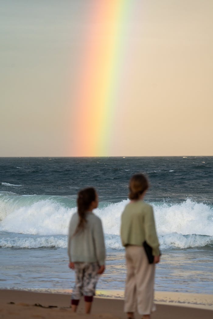 Crafting Captivating Headlines: Your awesome post title goes here Two children watching a rainbow over the ocean waves on a sandy beach.