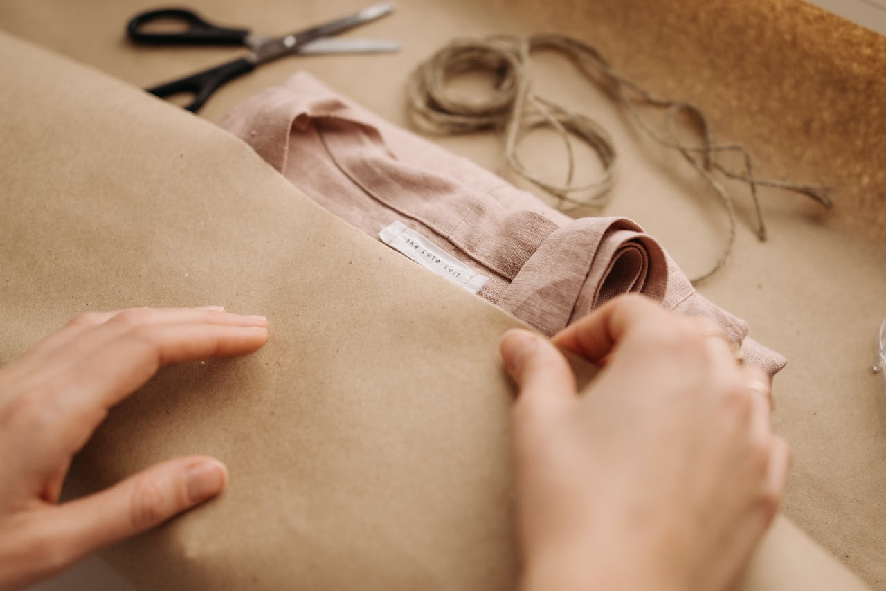The Art of Drawing Readers In: Your attractive post title goes here Close-up of hands wrapping a linen shirt with twine, showcasing craftsmanship and sustainable fashion.